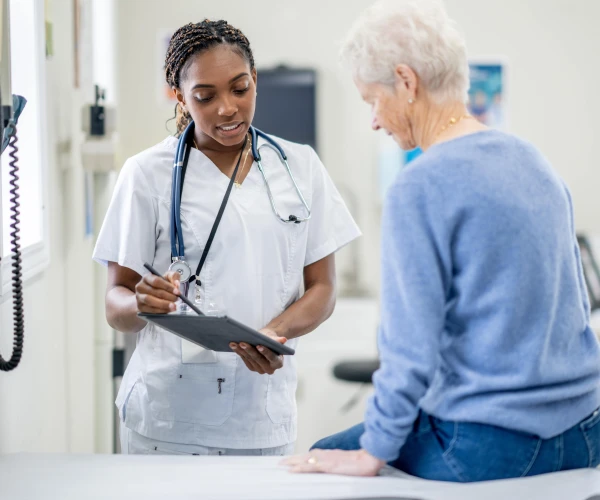 A physician showing an elderly patient her clipboard during an appointment